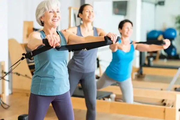 Toning Arms After 60: Empowering Womens Fitness Through Effective Weight Training 2 older woman doing weight training Beaconsfield and resistance in the gym to tone upper arms