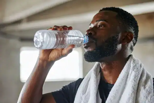 Image of man drinking water to improve hydration Beaconsfield after work out.